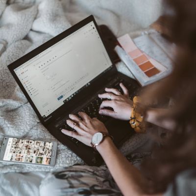 Adult woman typing on a laptop in a cozy home setting, emphasizing remote work and comfort.